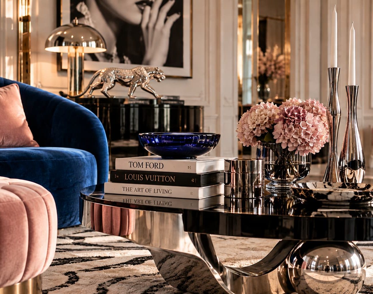 Interior detail with navy velvet seating, blush upholstery, black marble table, chrome panther sculpture and polished metallic accessories